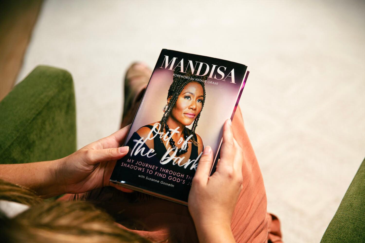 Woman on a couch reading Mandisas book